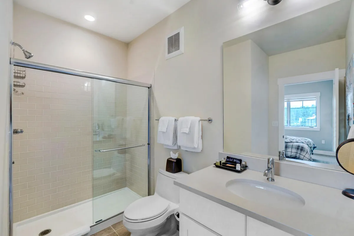 A modern bathroom showcasing a glass shower enclosure, a sleek sink with a contemporary faucet, and plush towels on a rack. The ambiance is serene and spa-like, emphasizing comfort and refreshment.